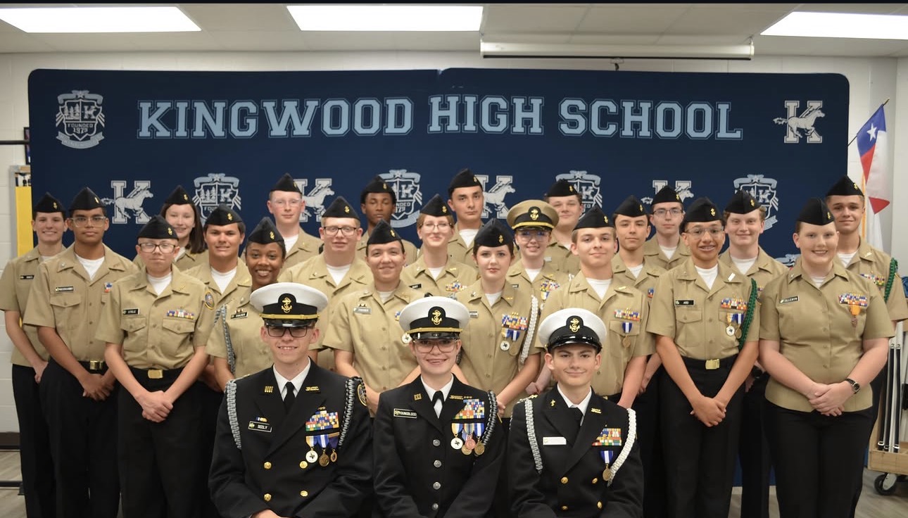 Kingwood High School NJROTC company staff and cadets in uniform posed in front of the Kingwood High School banner