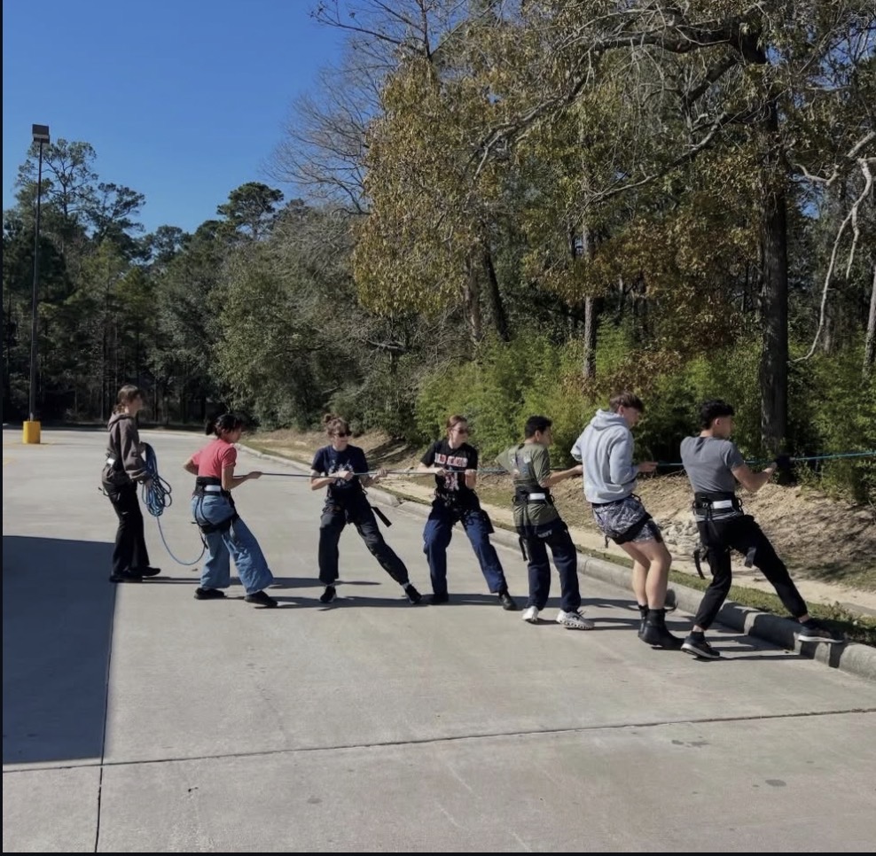 Kingwood NJROTC raider cadets in harnesses hauling a rope line during team training